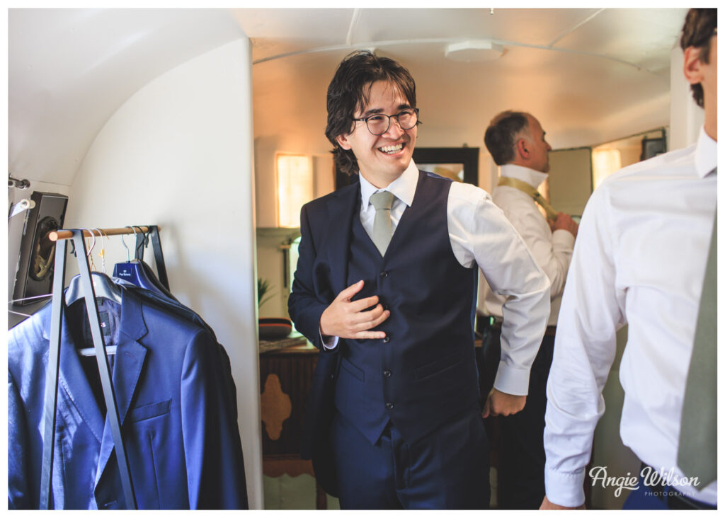 Groom putting on jacket at the Lyons Farmette